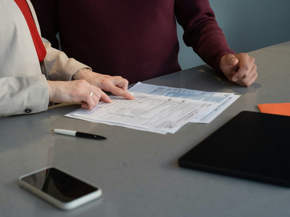 Duas pessoas revisando documentos sobre uma mesa